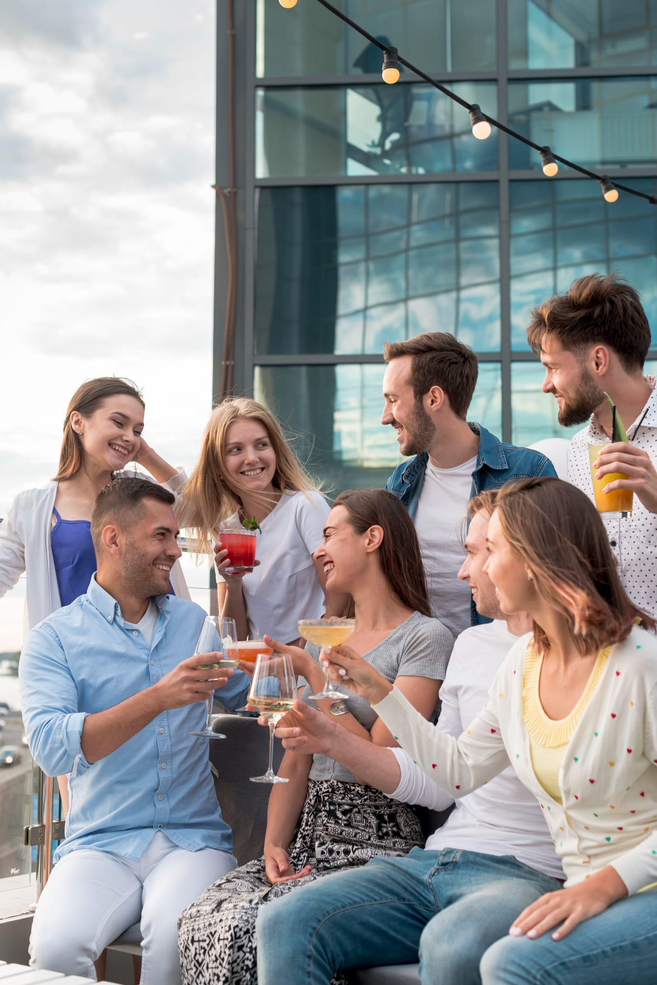 Friends enjoying rooftop party with drinks at modern outdoor terrace